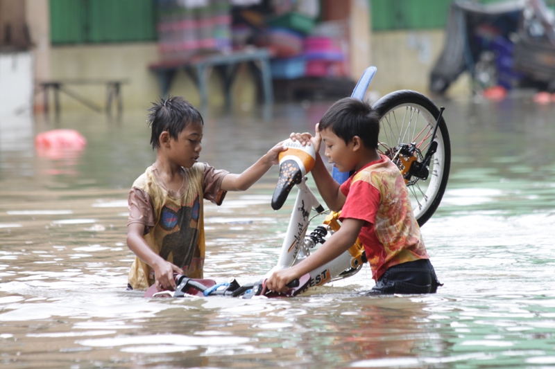 Anak-Anak sedang bermain di tengah banjir yang sedang melanda Bekasi