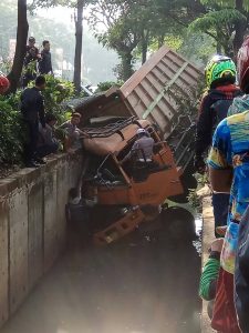 Diduga Supir Mengantuk, Truk Muatan Batu Terjungkal di Saluran Air Summarecon